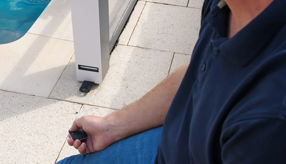 Personne appuyant sur une télécommande pour ouvrir un abri de piscine