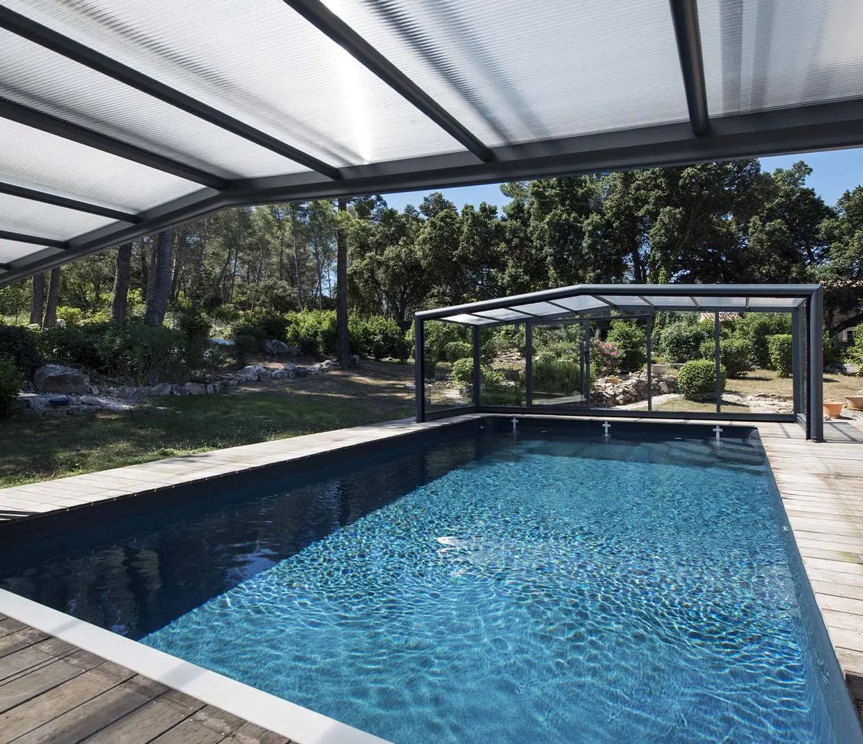 Piscine avec terrasse en bois et abri de piscine ouvert sur les deux côtés