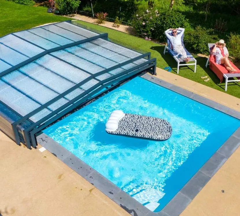 Couple au bord d'une piscine couverte par un abri de piscine bas