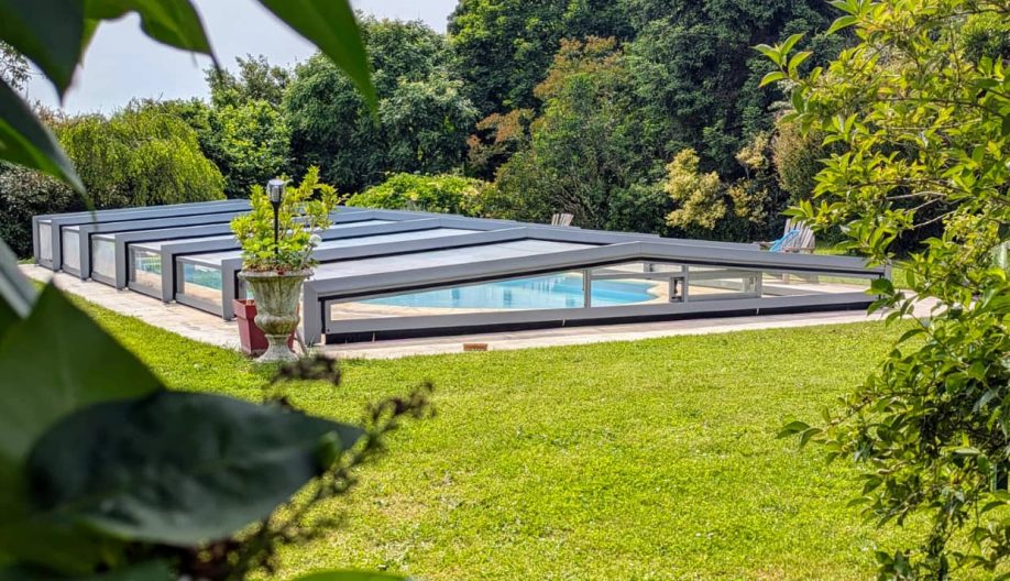Jardin verdoyant avec une piscine protégée par un abri