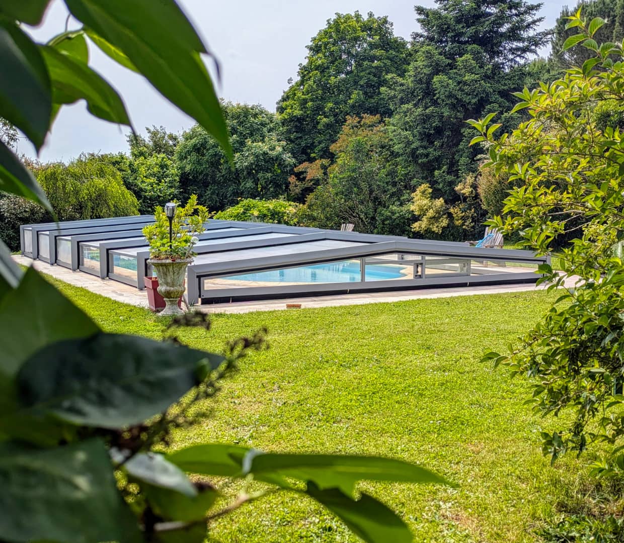 Jardin verdoyant avec une piscine protégée par un abri