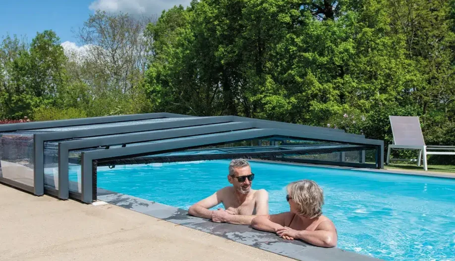 Couple se baignant en se regardant dans une piscine avec un abri replié