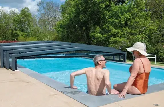 Couple se baignant dans une piscine avec un abri de piscine semi-ouvert