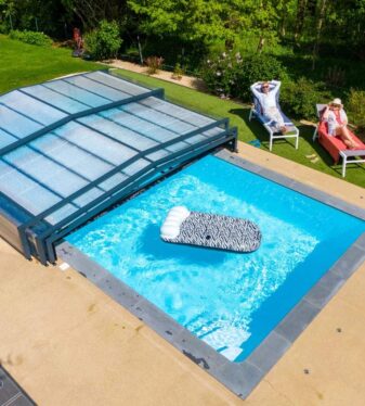Couple au bord d'une piscine couverte par un abri de piscine bas