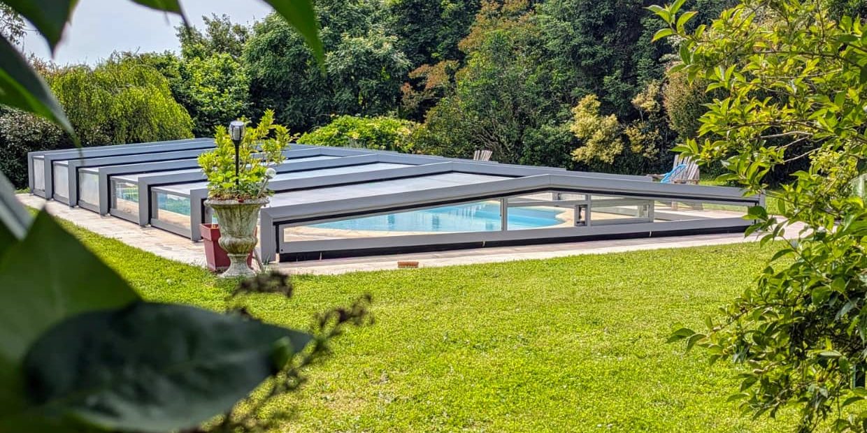 Jardin verdoyant avec une piscine protégée par un abri